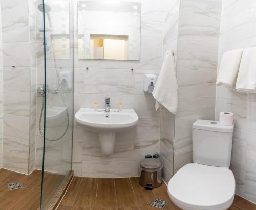 a white bathroom with a sink and a toilet at Supreme Victoria in Varna City