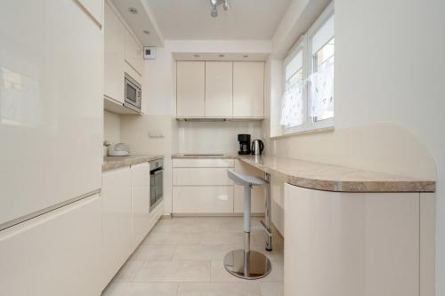 a white kitchen with white cabinets and a counter at Beautiful Apartment with a Spacious Balcony in Wrocław by Renters in Wrocław
