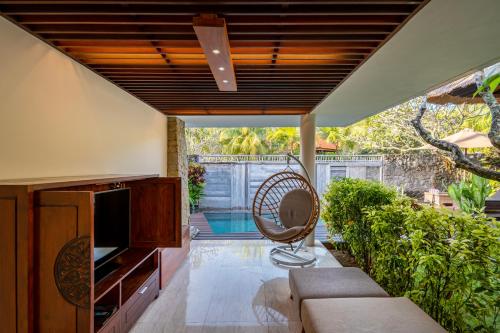 an outdoor living room with a couch and a fan at MERUSAKA Nusa Dua in Nusa Dua