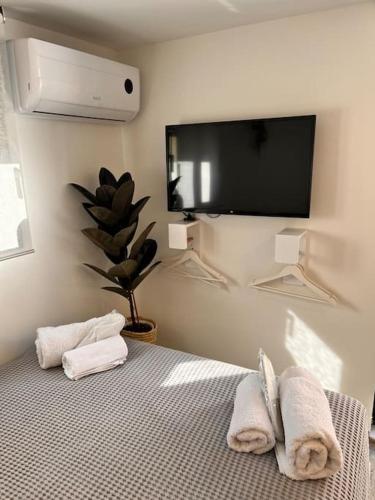 1 dormitorio con 1 cama con toallas y TV de pantalla plana en Athena 2 en Athens