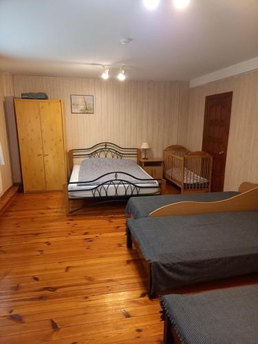 a bedroom with two beds and a wooden floor at Aido ir Jovitos sodyba Jorunas in Kernavė
