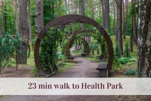 a walk to health park with a wooden arch and benches at Cozy Center Druskininkai in Druskininkai