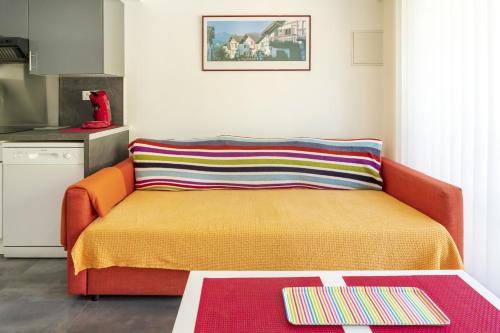 - un canapé orange avec un oreiller coloré dans la cuisine dans l'établissement Appartement de charme - spa privé, à Biarritz