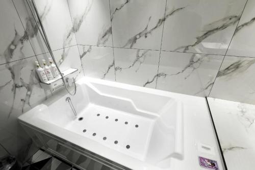 a white sink in a bathroom with marble walls at Hotel In Modern in Cheongju