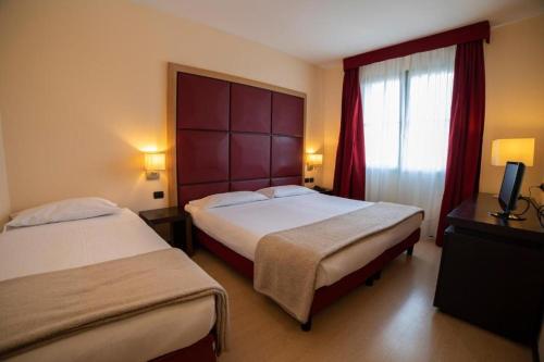 a hotel room with two beds and a window at ALBA HOTEL in Reggio Emilia