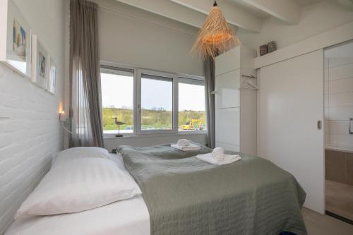 um quarto com uma cama com lençóis brancos e uma janela em Vakantiehuis - Lepelblad 97 - Nieuwvliet-Bad em Nieuwvliet