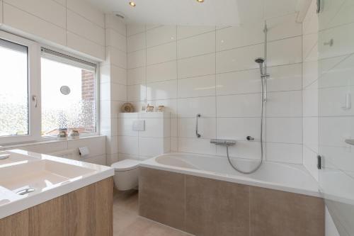 ein Badezimmer mit Badewanne, Toilette und Waschbecken in der Unterkunft Welcome in - Vakantiehuis - Lepelblad 97 - Nieuwvliet-Bad in Nieuwvliet