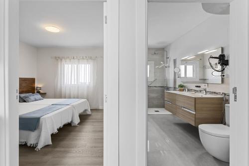 a bedroom with a bed and a bathroom with a sink at Casa Azul by Escape Home in Punta de Mujeres