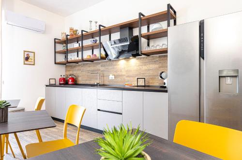 a kitchen with white cabinets and yellow chairs and a table at B&B Corsini in Bologna