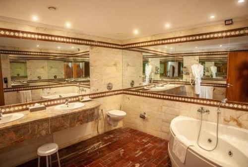 uma casa de banho com 2 lavatórios, uma banheira e um WC. em Tunis Grand Hotel em Tunes