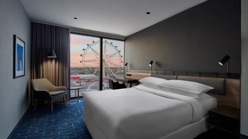 a hotel room with a large white bed and a desk at Vibe Melbourne Docklands in Melbourne