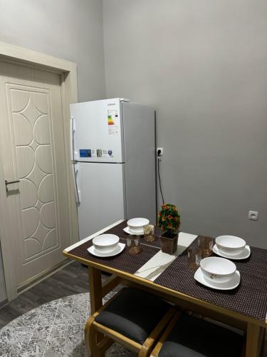 a kitchen with a table with plates and a refrigerator at City Plaza Zarhal in Samarkand