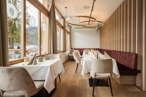 a restaurant with white tables and chairs and windows at Heritage Hotel Hallstatt in Hallstatt