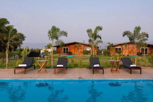 a pool with chairs and a table next to a house at Aveeno Resort with Swimming Pool Near Calangute & Baga in Goa