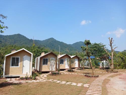 a row of cottages with mountains in the background at Halo Retreat in Hòa Bình