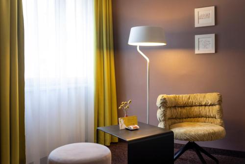 a living room with a chair and a lamp and a table at Boutique Hotel Das Tigra in Vienna