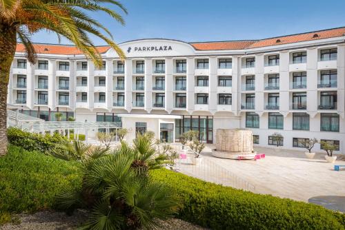 a large white building with a palm tree in front of it at Park Plaza Histria Pula in Pula