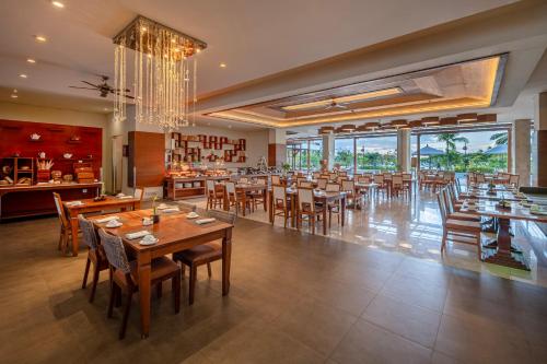 a restaurant with wooden tables and chairs and a chandelier at MERUSAKA Nusa Dua in Nusa Dua
