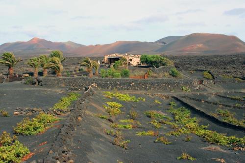 un pueblo en el desierto con montañas en el fondo en Casa Rural Vega de Timanfaya en Uga