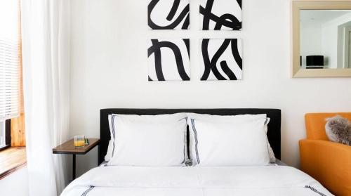 1 dormitorio con 1 cama con sábanas blancas y silla naranja en 1597-6 Luxury Studio Upper East Side W&D, en Nueva York