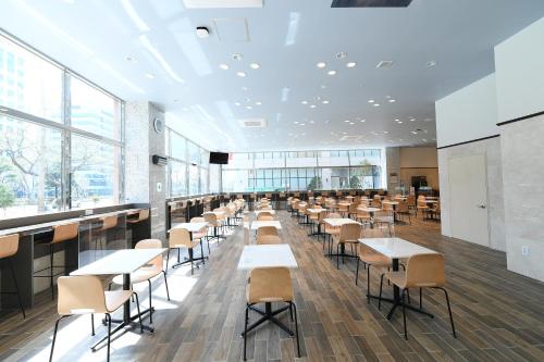 昌原市にあるToyoko Inn Changwonのカフェテリア(テーブル、椅子、窓付)