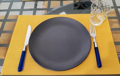 a black plate with a fork and knife on a table at Trapani Emotions apartment in Valderice