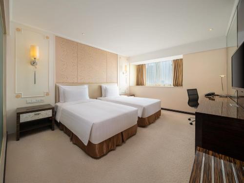 a hotel room with two beds and a flat screen tv at Dorsett Chengdu in Chengdu