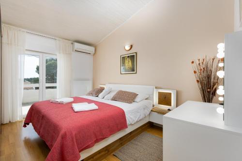 een witte slaapkamer met een groot bed met een rode deken bij Apartment Neda in Krk
