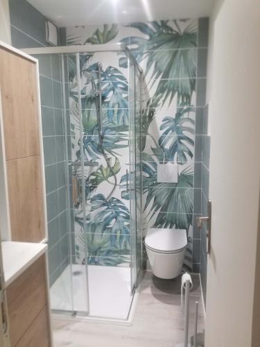 uma casa de banho com um chuveiro e um WC com um mural de folhas em Cocon RDC calme cœur historique em Périgueux
