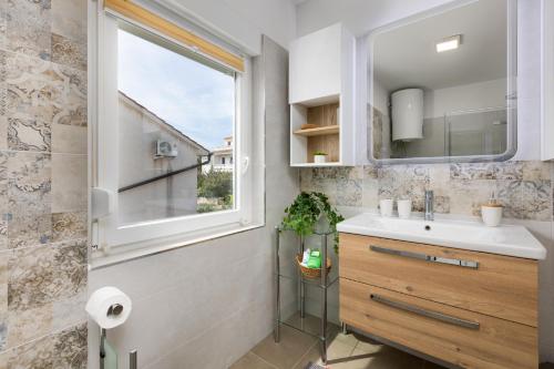 La salle de bains est pourvue d'un lavabo et d'une fenêtre. dans l'établissement Apartment Neda, à Krk