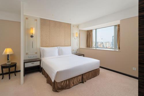 a bedroom with a large white bed and a window at Dorsett Chengdu in Chengdu