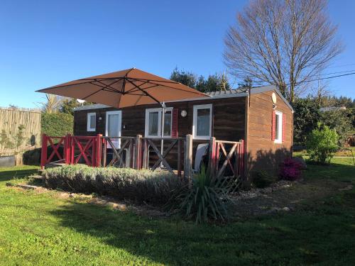 a tiny house with an umbrella in a yard at Les chalets de Bes Le Montagnol in Lacombe