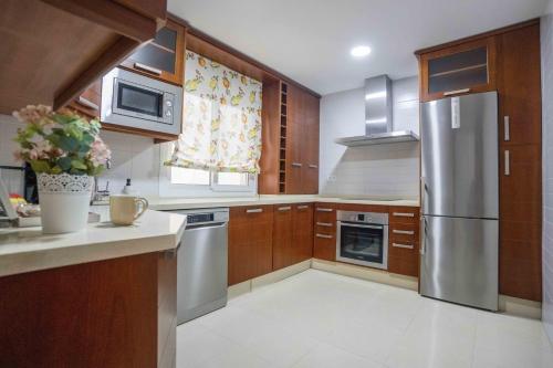 uma cozinha com armários de madeira e electrodomésticos de aço inoxidável em Prada Suite Home em Córdoba