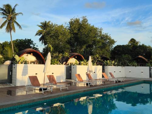 una fila de sillas y sombrillas junto a una piscina en Found Mansion, en Pantai Cenang
