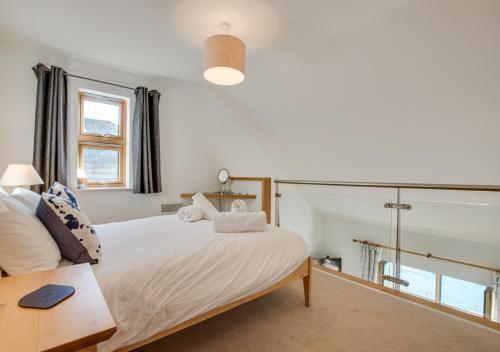 a bedroom with a large white bed with a table at Quayside in Porthleven