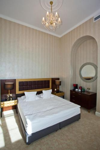 a bedroom with a large white bed and a chandelier at Tiffi Old Town Hotel in Warsaw