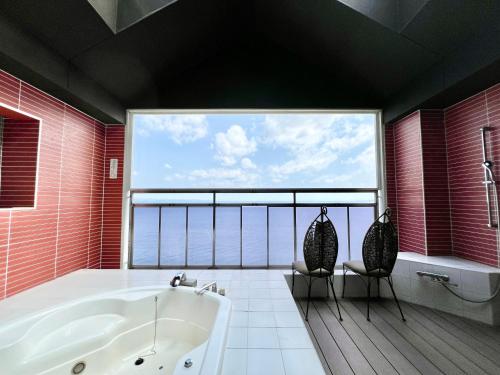 a bathroom with a tub and a large window at SKY Tower Sweet 4 Beppu, Resort Love Hotel in Beppu
