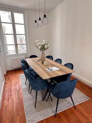 une table à manger avec des chaises et un vase de fleurs dans l'établissement Appartement cœur de ville, à La Flèche