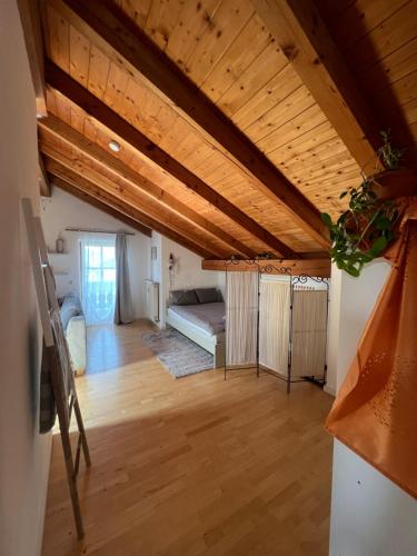 - un salon avec un lit et un plafond en bois dans l'établissement Gemütliche Dachgeschosswohnung mit Balkon, à Ainring