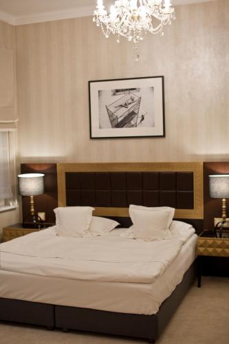 a bedroom with a large bed and a chandelier at Tiffi Old Town Hotel in Warsaw