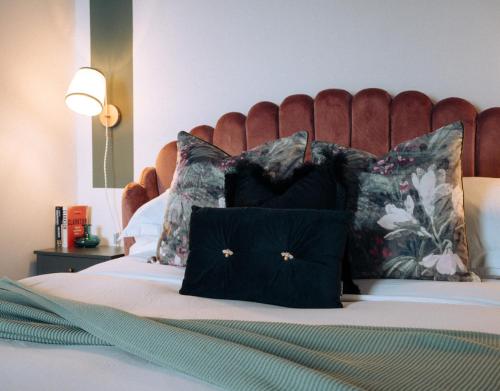 a bed with black pillows and a red headboard at Pebble View - Central Cosy with Sea-Views in Weymouth