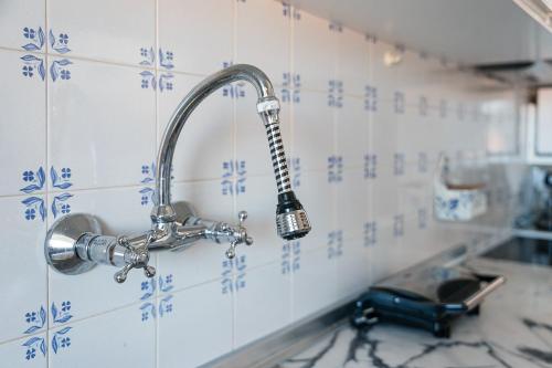 a kitchen sink with a faucet on a tiled wall at GuestReady - Pleasant Retreat in Moledo in Moledo