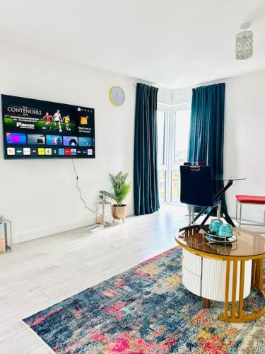 ein Wohnzimmer mit einem TV und einem Tisch in der Unterkunft Modern Flat with En-suite and Free Parking in Chatham