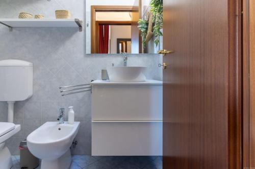 ein Badezimmer mit einem Waschbecken, einem WC und einem Spiegel in der Unterkunft [Posizione Strategica-Cosmè Tura] in Ferrara