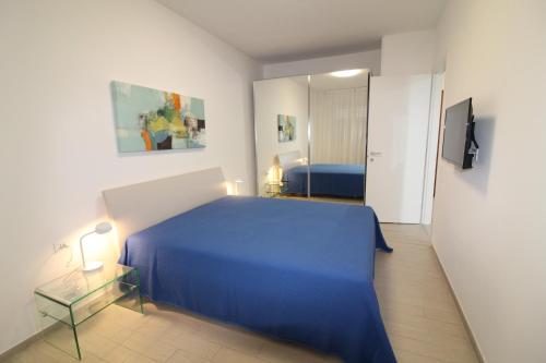 a bedroom with a blue bed and a mirror at Appartamenti Luna in Lignano Sabbiadoro