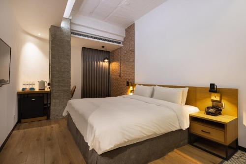 a bedroom with a large white bed and a table at BlueSky Hotel in Taichung