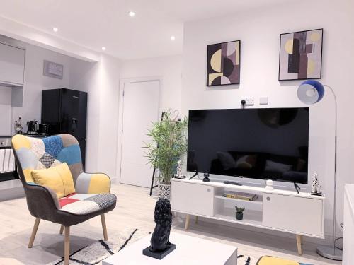 a living room with a flat screen tv and chairs at 2 BED 1 BATH LUXURY STAY APARTMENT 20 Mins drive to Central London 10 Min Drive to Wembley Stadium Free Parking in Golders Green