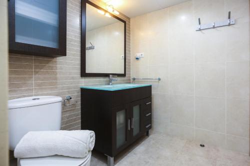 uma casa de banho com um lavatório, um espelho e um WC. em BRISA Planet Costa Dorada em La Pineda