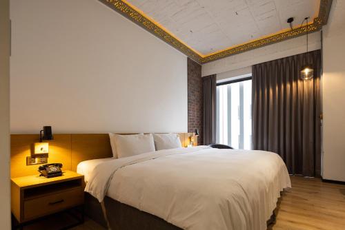 a bedroom with a large white bed and a window at BlueSky Hotel in Taichung
