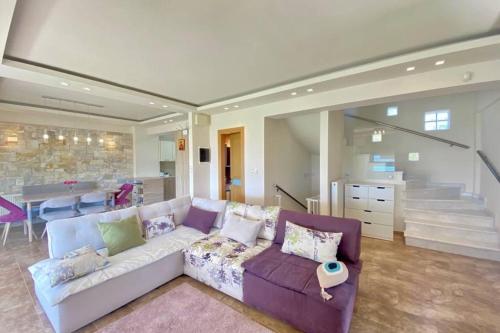 a living room with a purple couch and a kitchen at TAMARI Luxury Villa - Miramare in Pefkohori